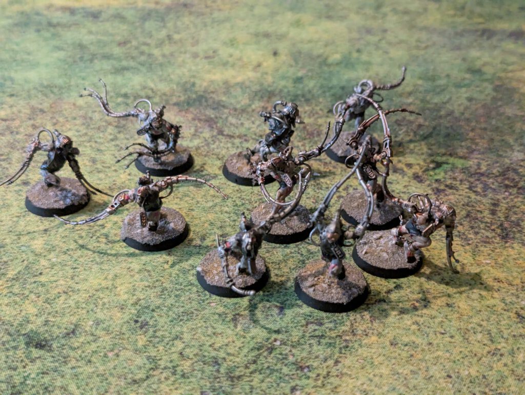 Ten painted Arco-Flagellants with whips and implants, top-front view.