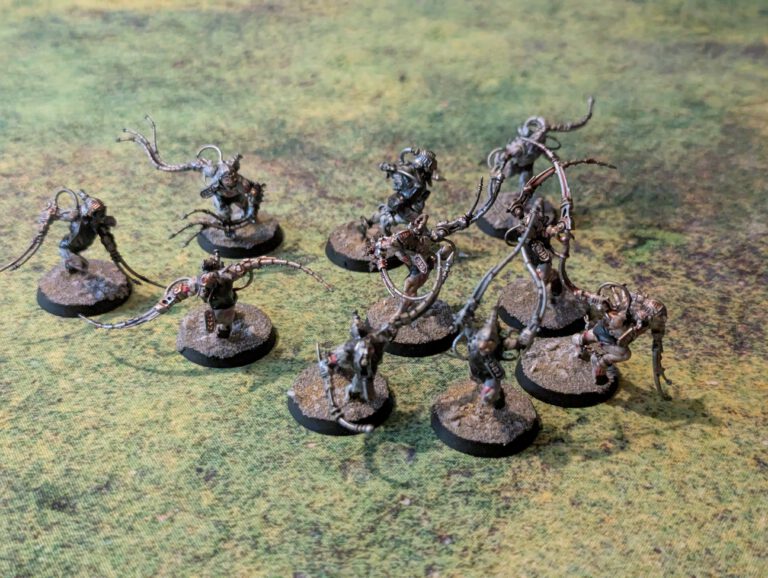 Ten painted Arco-Flagellants with whips and implants, top-front view.
