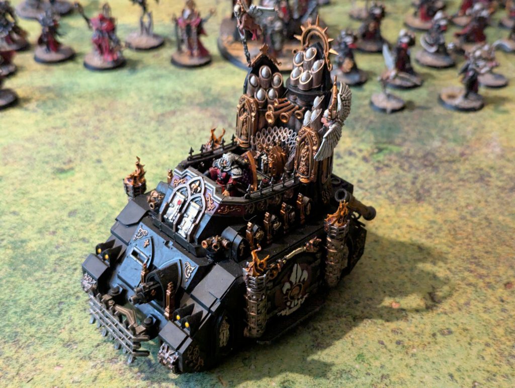 Painted Adepta Sororitas Exorcist tank with organ pipes, viewed from top-front angle on tabletop surface.