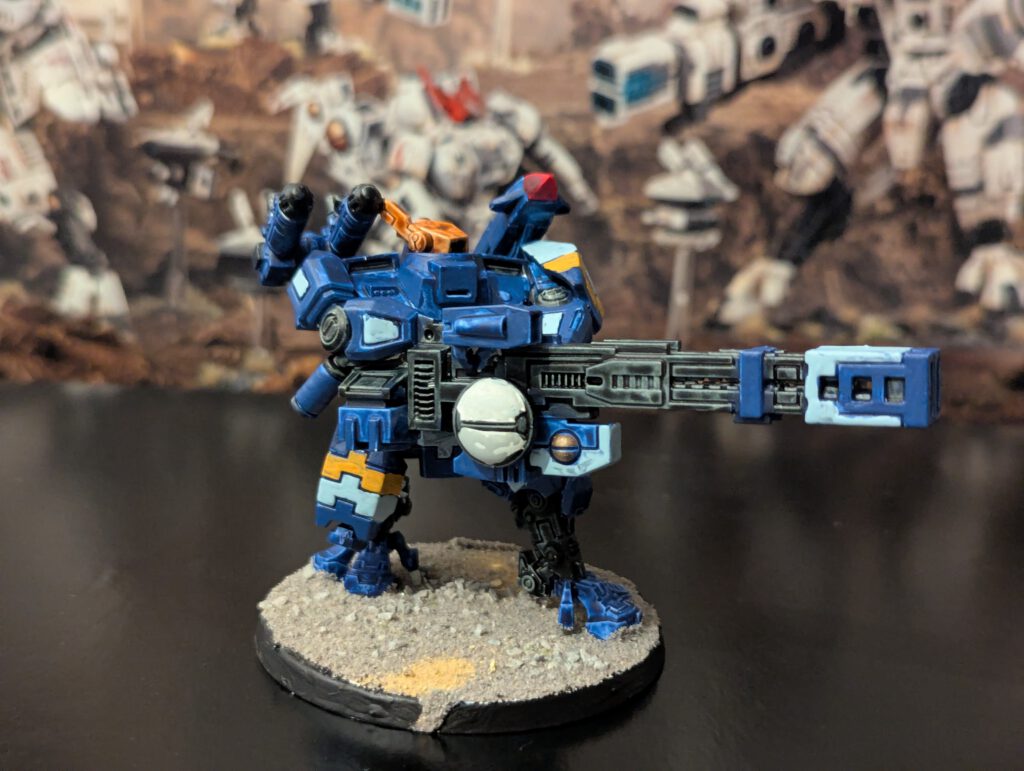 Painted T’au Broadside Battlesuit with heavy armaments, viewed from a slightly elevated front angle.