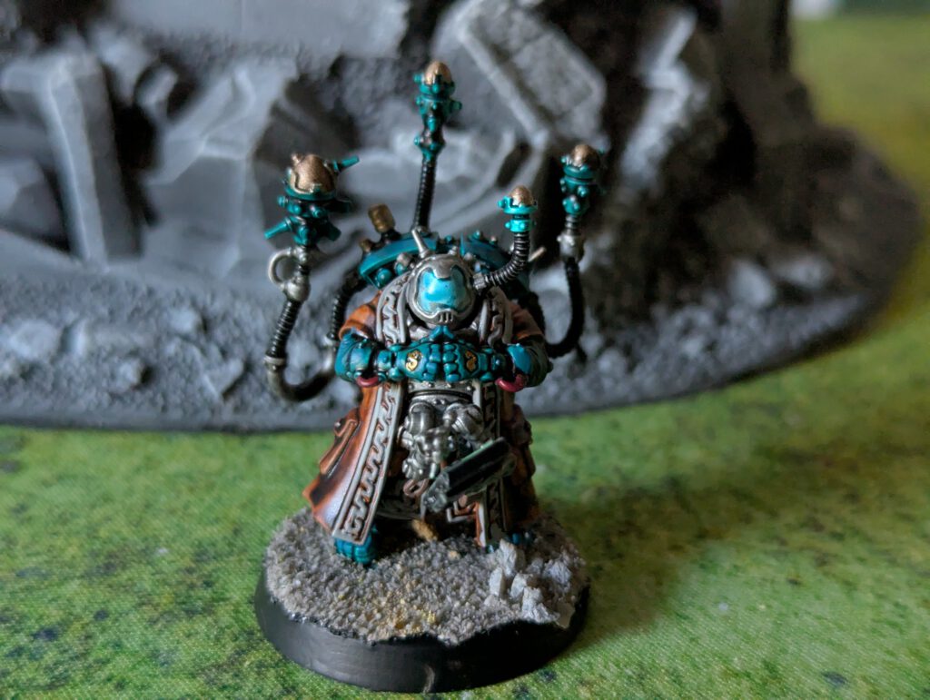 Painted Memnyr Strategist miniature viewed from a top-front angle, showing detailed armor and cloak.