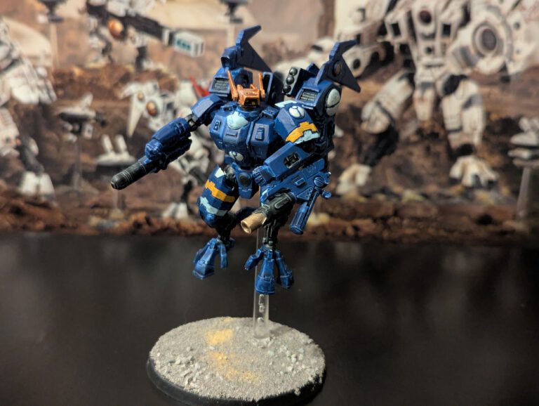 Painted T’au Commander in Enforcer Battlesuit, shown from a top-front angle with full weapon loadout visible.