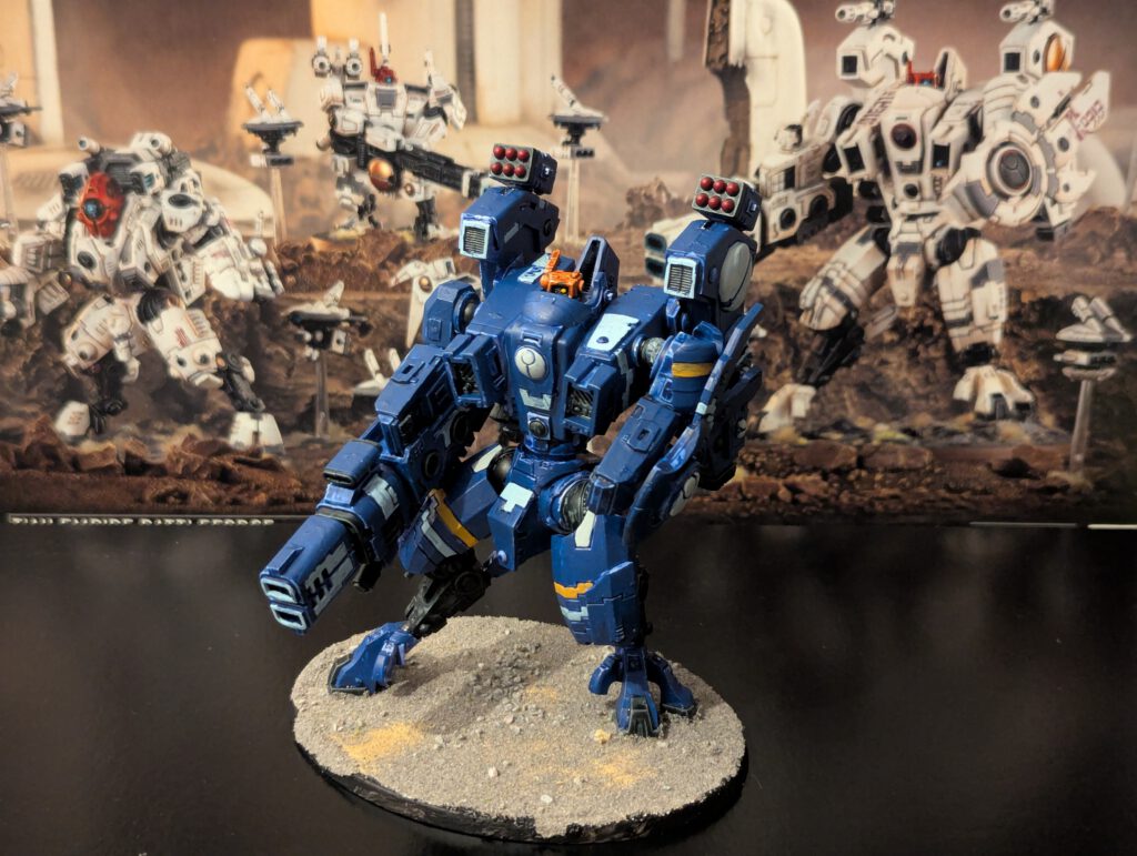 Painted T’au Riptide Battlesuit with heavy weapons, shown from a slightly elevated front angle.