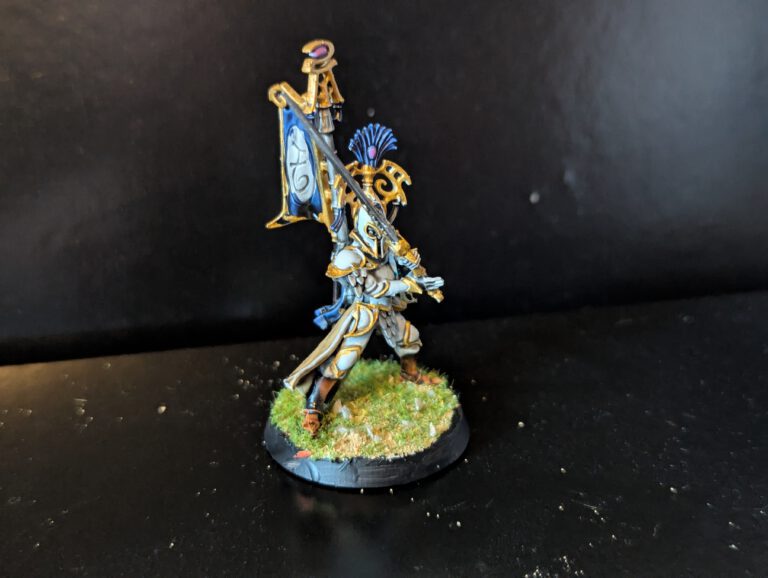 Side view of a Lumineth Bladelord showcasing the clean white highlights and the contrast with the desert base.