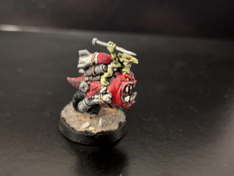 A painted Orks Bomb Squig with explosives strapped to its back.