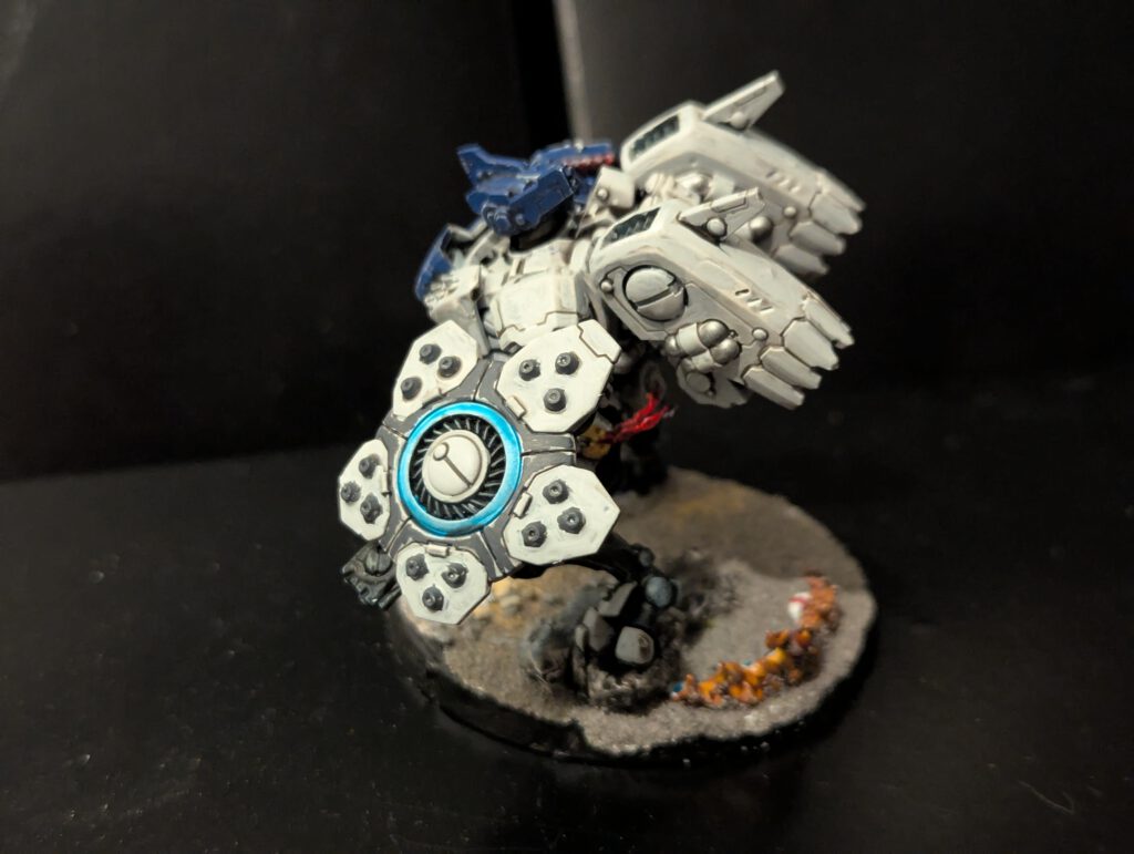 Side profile of a T'au Battlesuit from the Twin Lance highlighting the jetpack and leg pose.