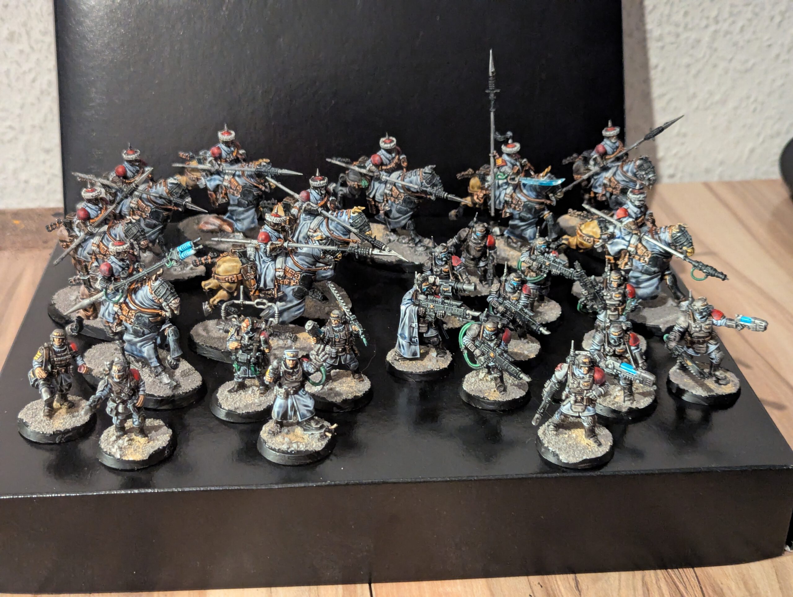 A wide group shot of a fully painted Astra Militarum army on a gaming table, including Kasrkin, Attilan Rough Riders, and a Cadian Command Squad.