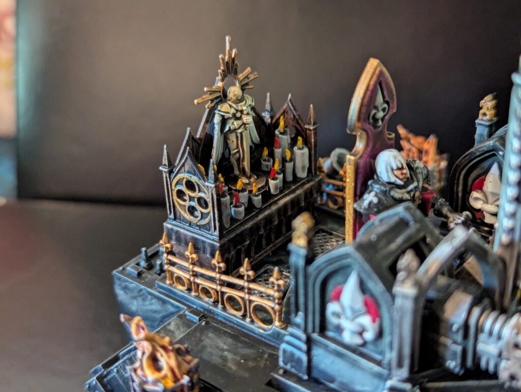 Macro shot of the rear of the Immolator, focusing on the miniature candles with flickering flame effects and the golden statue within the gothic alcove.