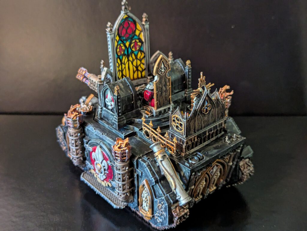 The rear of the Adepta Sororitas Immolator, showcasing the gothic architectural elements, additional gold filigree, and the full scale of the stained-glass housing.