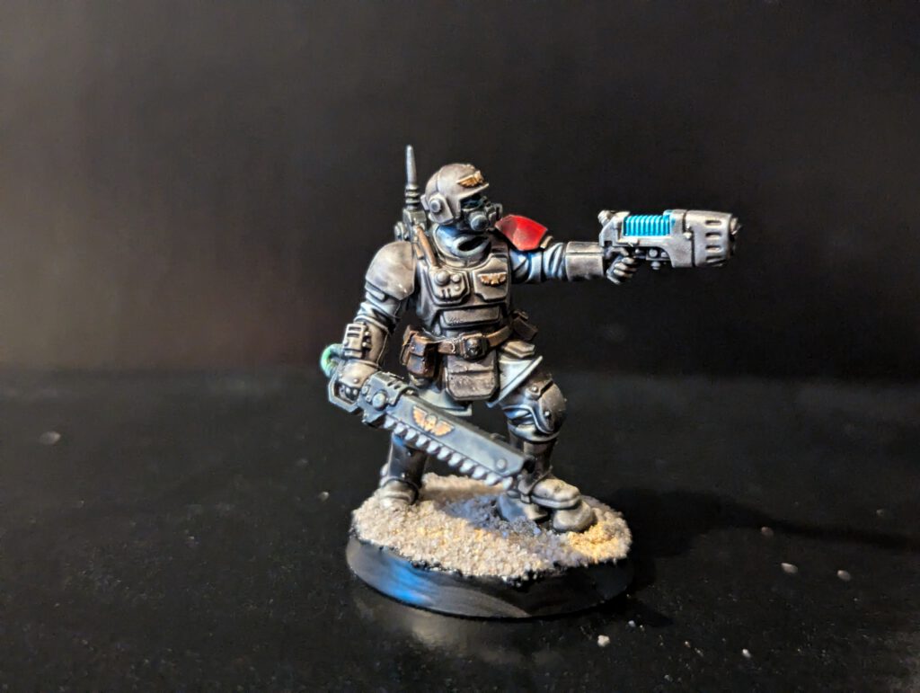 Painted Kasrkin Sergeant holding a chainsword and hot-shot laspistol, featuring crisp edge highlights on the carapace armor.