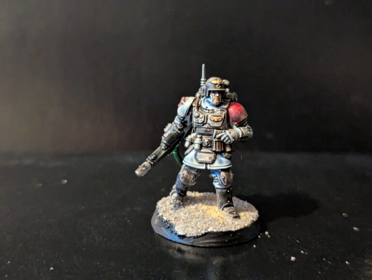 Standard Kasrkin special forces trooper aiming a hot-shot lasgun with a grey and blue armor scheme.